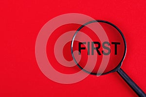 Magnifying glass with the inscription FIRST on a red background