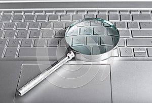 Magnifying glass on laptop keyboard. Information search concept. Digital databases study. Audit conducting using
