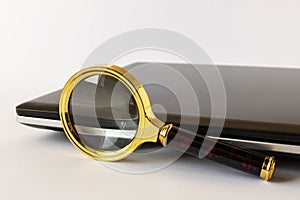 Magnifying glass and laptop on a light background. The concept of searching for information on the Internet. Selective focus