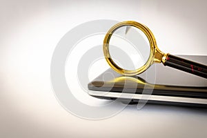 Magnifying glass and laptop on a light background. The concept of searching for information on the Internet. Selective focus
