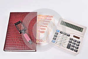 Magnifying glass lies on the diary with bookmarks of banknotes next to the calculator