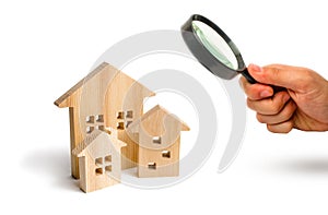 Magnifying glass is looking at the City of wooden houses on a white background. The concept of urban planning, infrastructure proj