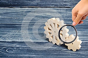 Magnifying glass is looking at the Gears of wood stand on a dark wooden background. Concept of technology and industry