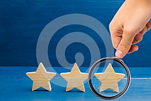 Magnifying glass is looking at the rating of the hotel, restaurant, mobile application. Three stars on a blue background. The conc