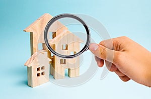 Magnifying glass is looking at the Three houses. Buying and selling of real estate, construction. Apartments and apartments. City