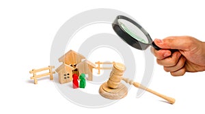 Magnifying glass is looking at the Wooden apartment house with people, keys and a judge hammer on a white background. The concept