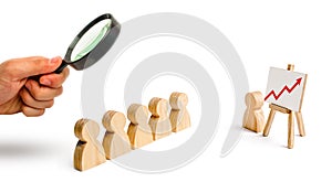 Magnifying glass is looking at the Wooden figures of people stand in the formation and listen to their leader.