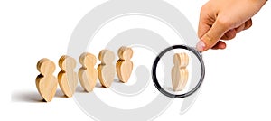 Magnifying glass is looking at the Wooden figures of people stand in the formation and listen to their leader. Business training,