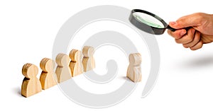 Magnifying glass is looking at the Wooden figures of people stand in the formation and listen to their leader. Business training