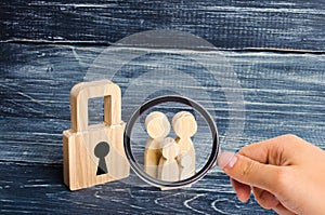 Magnifying glass is looking at the young family with children is standing near a wooden padlock. concept of a strong family