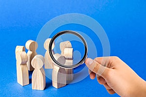 A magnifying glass looks at a people figurines stand in a circle. discussion, cooperation. Meeting at work