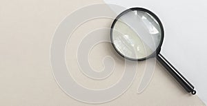 Magnifying glass or loupe on pale blue and beige background. Magnifier banner with copy space