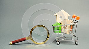 Magnifying glass and miniature wooden houses. House searching concept. Home appraisal. Property valuation. Choice of location for