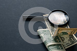 Magnifying glass and money on black background. Paper currency. Looking For Money