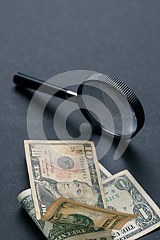 Magnifying glass and money on black background. Paper currency. Looking For Money