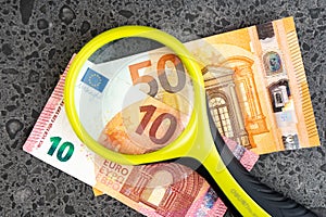 Magnifying glass and money euro isolated on stone background