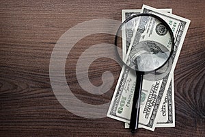 Magnifying glass and money on wooden background