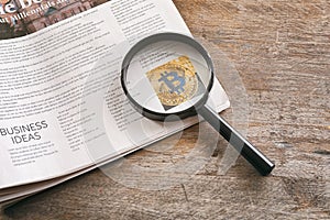 Magnifying glass and newspaper on wooden background