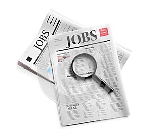 Magnifying glass and newspapers with headline JOBS on white background