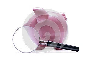 Magnifying glass next to a pink piggy bank