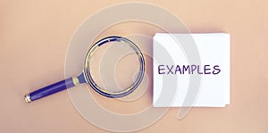 Magnifying glass and a note with the word Examples. Example, instance, sample. Business, marketing and training concept. Flat lay photo
