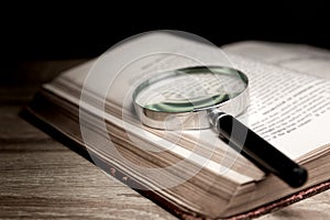 Magnifying glass on old books with wooden background