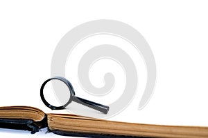 Magnifying glass on old empty book pages isolated on white background, space for text