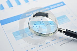 Magnifying glass over financial chart and graph business