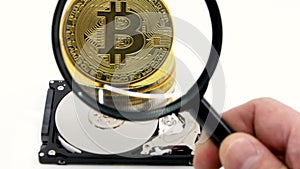 Magnifying glass over a gold bitcoin token.Worldwide virtual internet cryptocurrency and digital payment system.Digital coin money