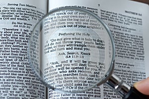 Magnifying glass over open Holy Bible Book, close-up, ask, search, knock verse, Matthew 7:7 Scripture text photo