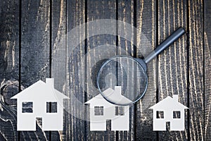 Magnifying glass and paper house on table