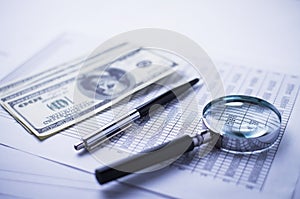 Magnifying glass, pen and analytical financial report lying on a table