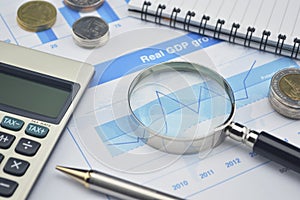 Magnifying glass, pen and calculator on financial chart and grap