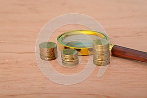 A magnifying glass placed upon a bed of coins, symbolizing financial development, banking accounts, statistical analysis,