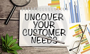 magnifying glass, plant, pen and a white notebook with the text uncover your customer needs