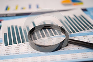 Magnifying glass on spreadsheet charts graphs paper. Financial development, Banking Account, Statistics, Investment Analytic