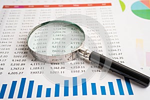 Magnifying glass on spreadsheet and graph paper. Financial development, Banking Account, Statistic, Investment Analytic research