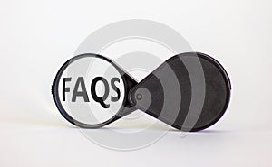 Magnifying glass with text `FAQS` on beautiful white background. Business concept, copy space