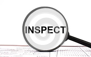 Magnifying glass with text INSPECT on financial tables