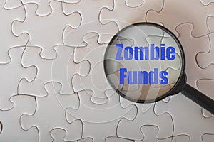 Magnifying glass with text ZOMBIE FUNDS.A zombie fund (more formally known as a closed fund) is a colloquial expression photo