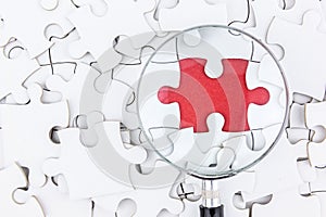 Magnifying glass to find piece of jigsaw puzzle