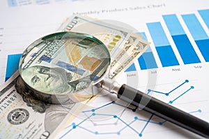 Magnifying glass with US dollar banknotes on charts graphs paper. Financial development, Banking Account, Statistics, Investment