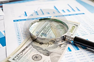 Magnifying glass with US dollar banknotes on charts graphs paper. Financial development, Banking Account, Statistics, Investment