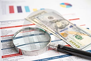 Magnifying glass and US dollar banknotes on spreadsheet and charts graphs paper. Financial development, Banking Account,