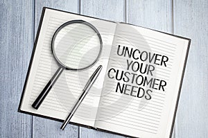 magnifying glass and a white notebook with the text uncover your customer needs