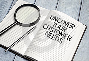 magnifying glass and a white notebook with the text uncover your customer needs