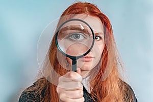 Magnifying glass. A woman's face through a magnifying glass. Big eyes. Research, choice concept