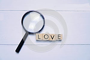 Magnifying glass and a wooden cube with letter LOVE.