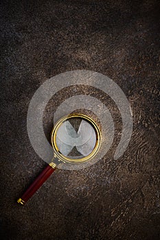 Magnifying glass with wooden handle on dark stone background