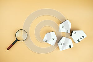 Magnifying glass and wooden houses on a yellow background. Search for housing